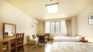 A hotel room with two beds, a desk, a chair, a small table, and a window with curtains. - Matsukaneya Annex (Yamagata)