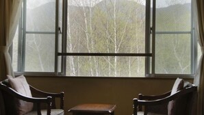 A room with a large window, two wooden chairs, and a small table. - Matsukaneya Annex (Yamagata)