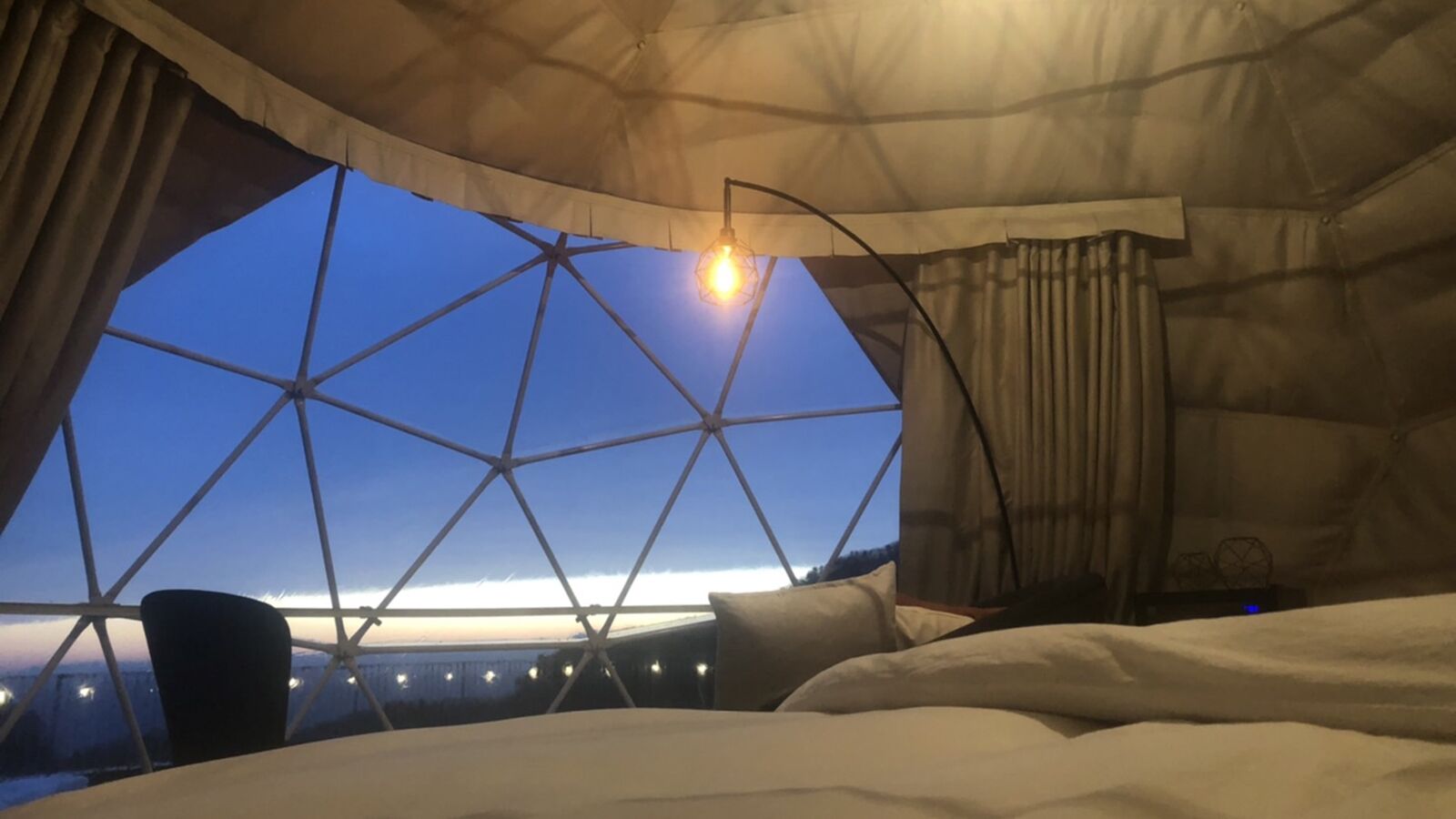 A room with a large window, a bed, and a chair.