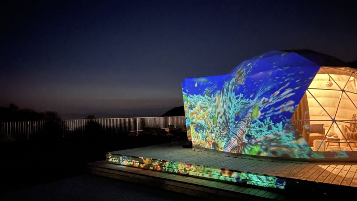 A modern building with a large projection screen displaying an underwater scene.