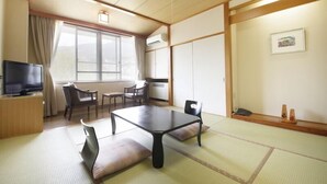 A traditional Japanese-style room with tatami flooring, a low table, and a television on a wooden cabinet. - Matsukaneya Annex (Yamagata)