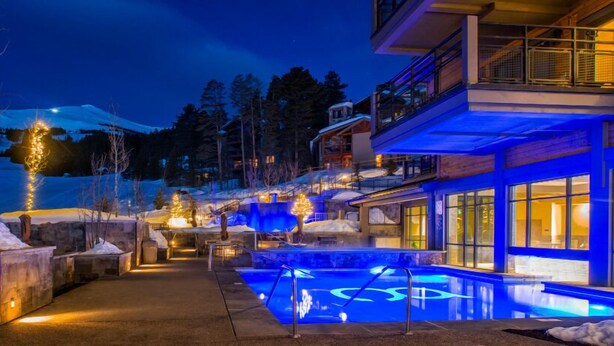A hotel with a pool area, outdoor lighting, and a snowy landscape.