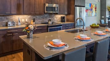 A modern kitchen with dark wood cabinets, stainless steel appliances, and a central island with seating.