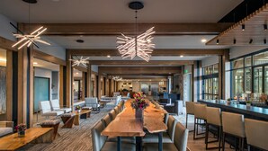 A modern hotel lobby with a long wooden reception desk, comfortable seating, and large windows.