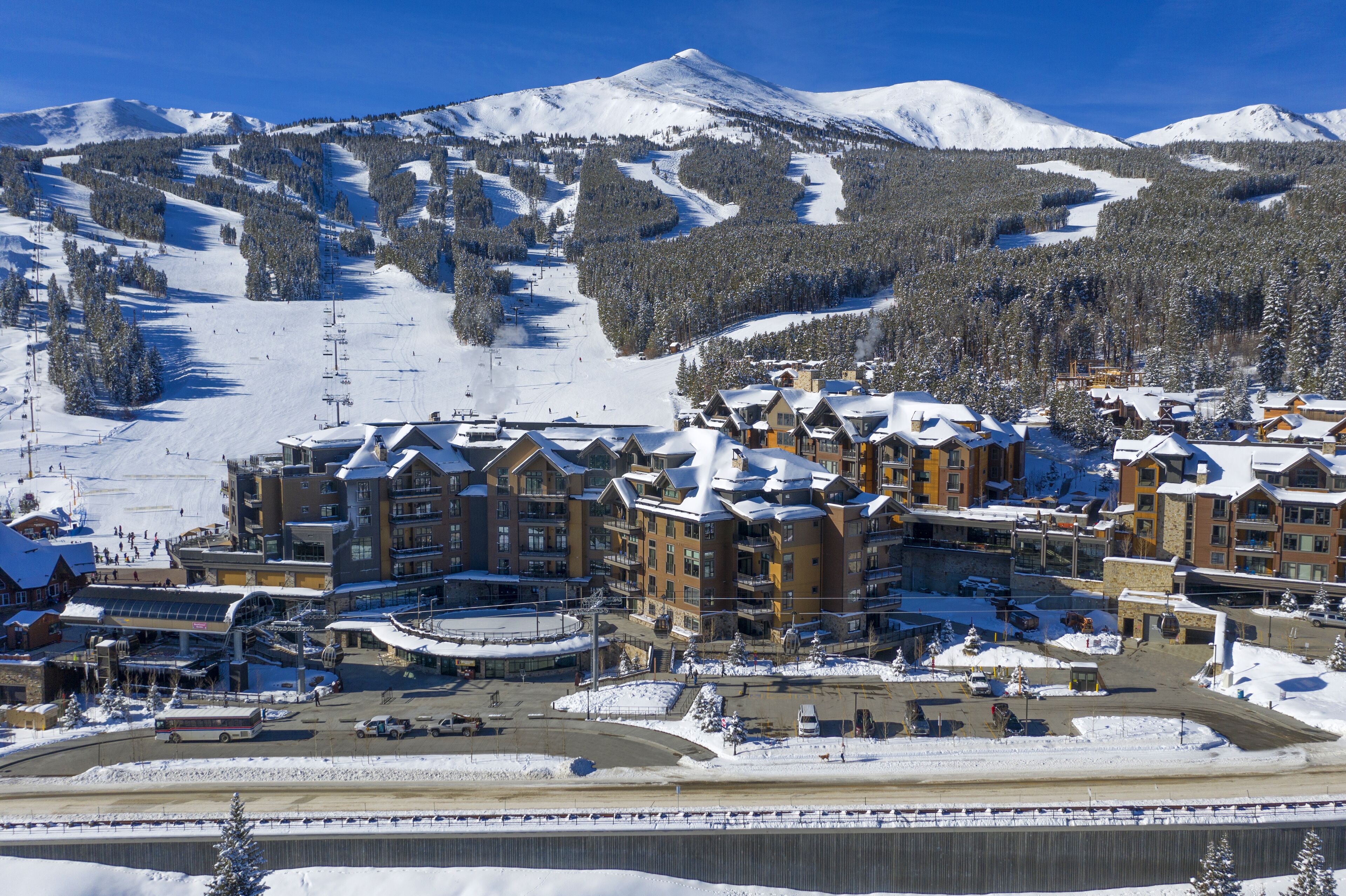 A ski resort with multiple lodging buildings, a ski lift, and a snow-covered mountain backdrop.