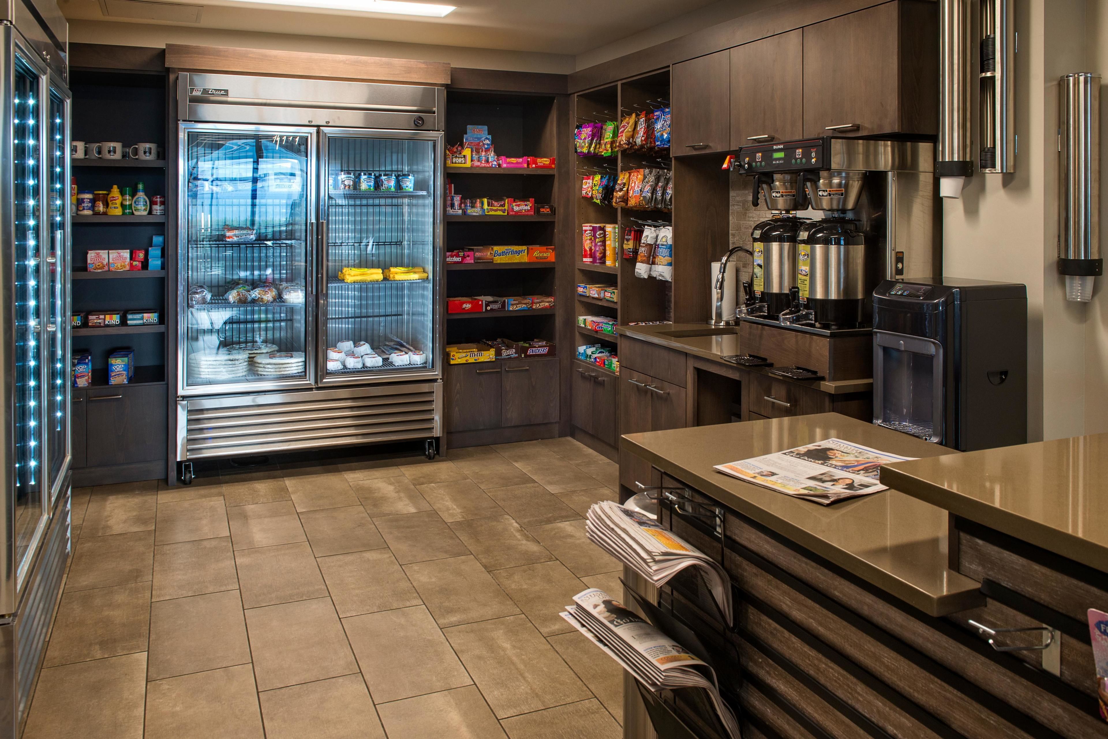 Una cocina moderna con refrigerador empotrado, cafetera y diversos alimentos en estantes.