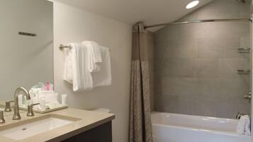 A bathroom with a sink, mirror, and bathtub.