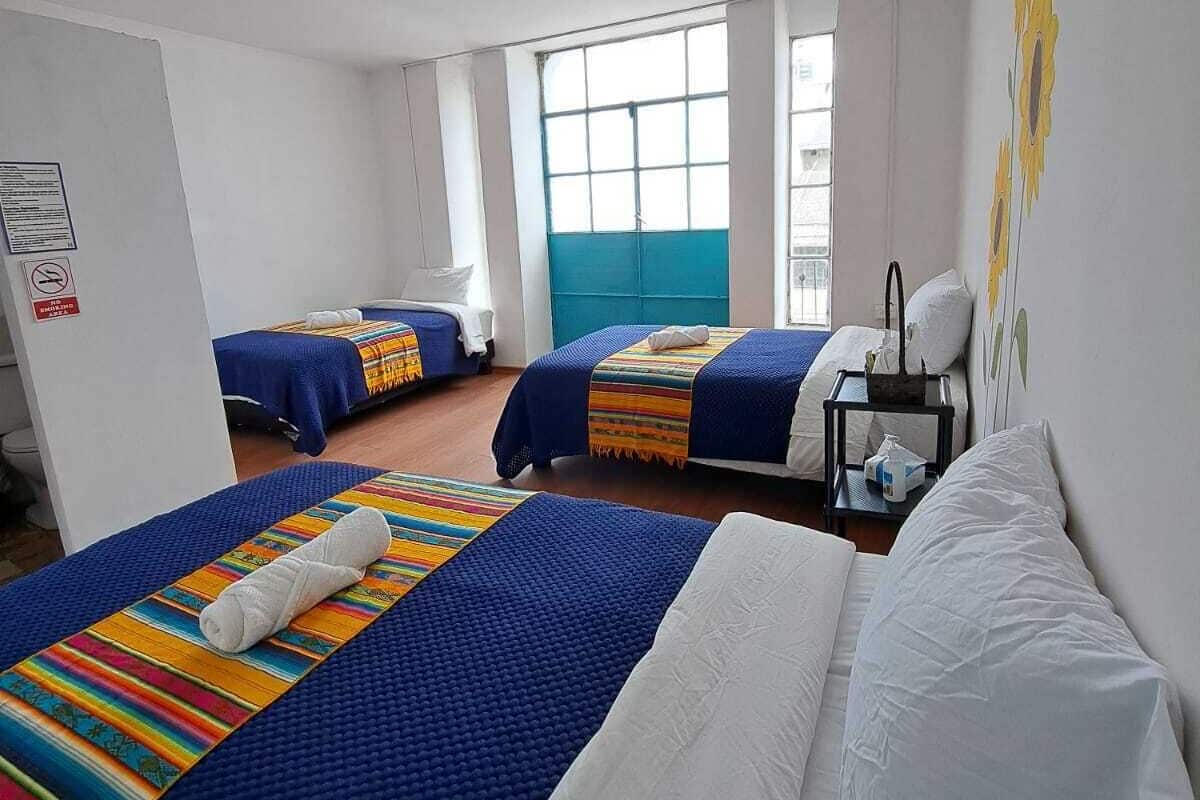 A hotel room with two beds, a window, and a wall with a sunflower mural.