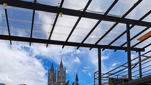 En tagterrasse med et bord og stole, udsigt til en historisk bygning, og en klar himmel.