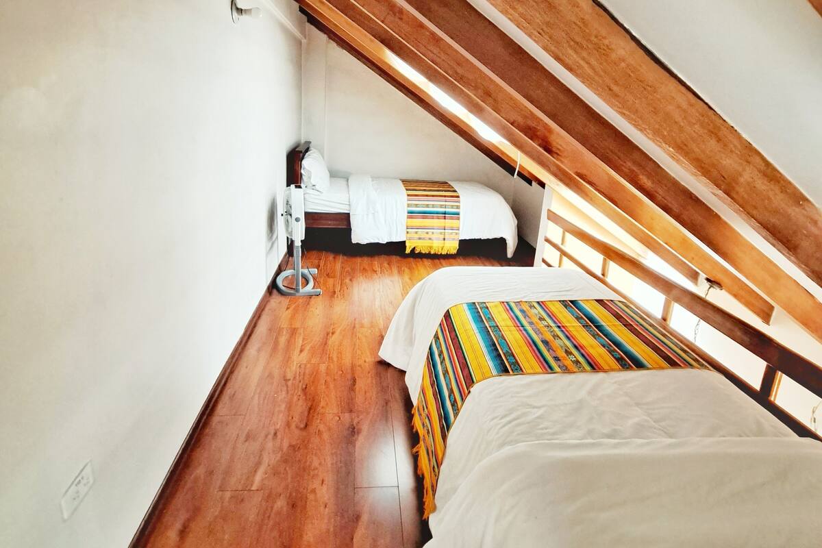 A small, cozy attic bedroom with a wooden ceiling and sloped walls.