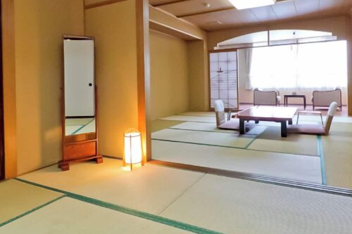 A tatami mat room with a bed, a mirror, and a lamp.