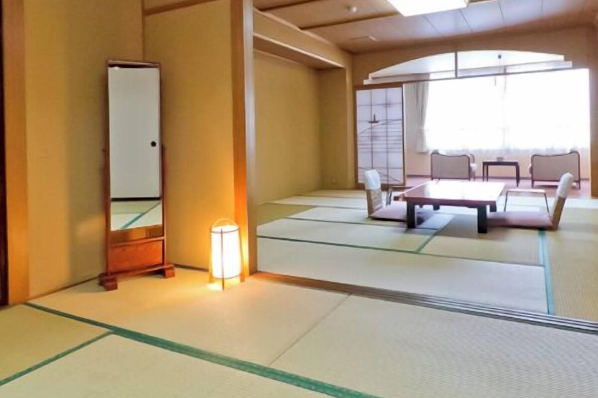 A tatami mat room with a bed, a mirror, and a lamp.