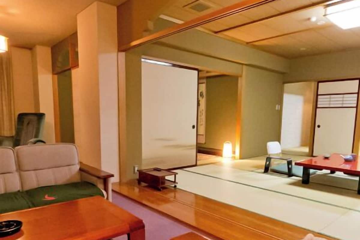 A traditional Japanese room with tatami flooring, a low wooden table, and a futon bed.