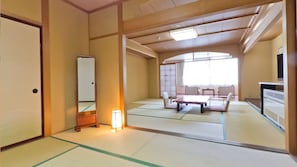 A traditional Japanese room with tatami flooring, a shoji screen, a low table, and a television.