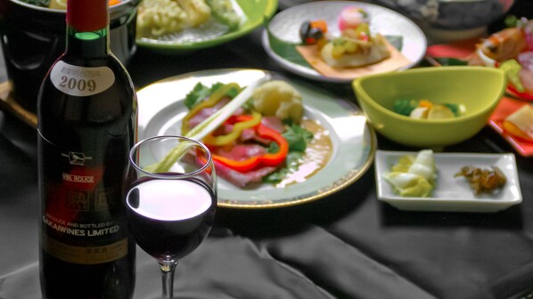 A bottle of wine, a glass of wine, and various dishes on a table. - Akayu Onsen Tansen Hotel (Nanyo)
