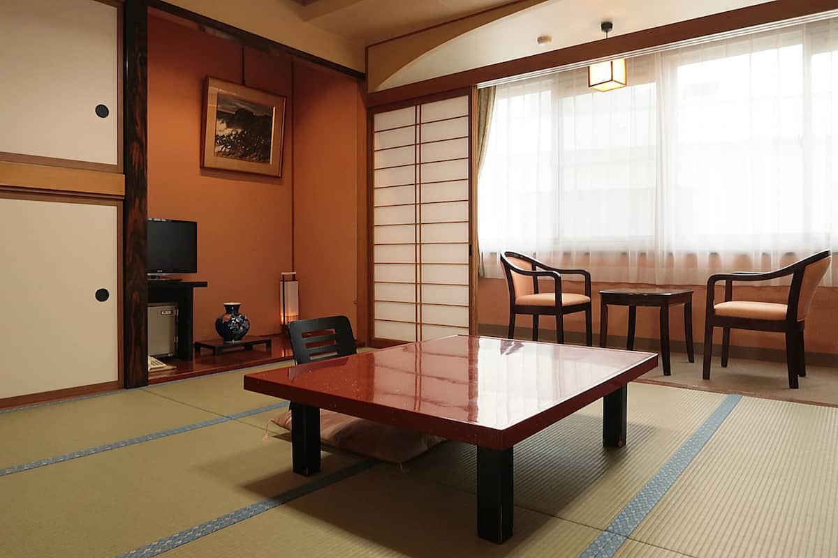 A traditional Japanese-style room with tatami flooring, a low table, and chairs.