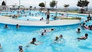 Une piscine dotée de plusieurs couloirs, entourée d’une terrasse en béton et d’arbres.