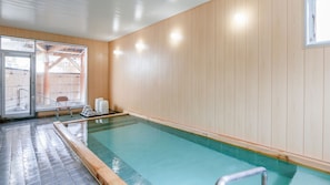 A swimming pool with wooden walls, a bench, and a chair outside.