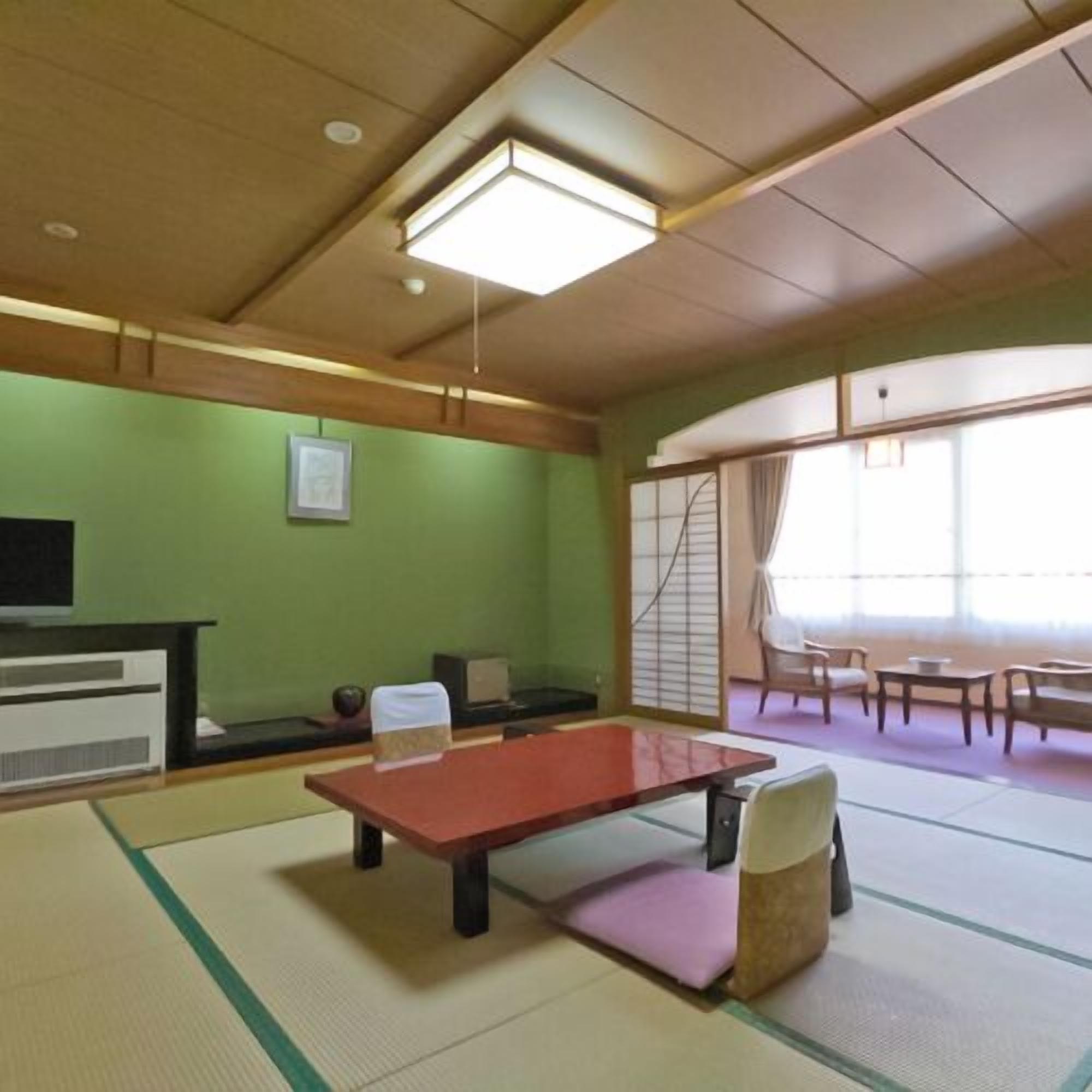 A tatami mat room with a tatami mat table, a low table, and a chair.
