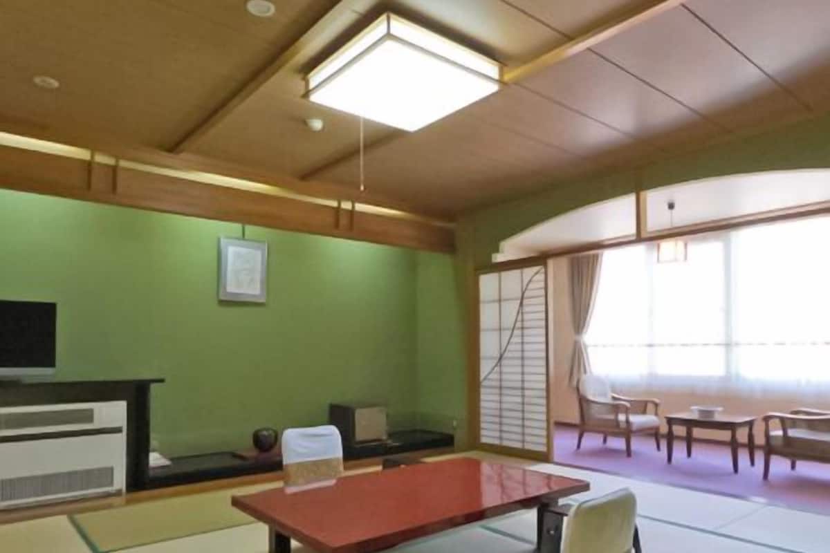 A tatami mat room with a tatami mat table, a low table, and a chair.
