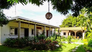 A two-story building with a covered porch and a garden path leading to a smaller structure.