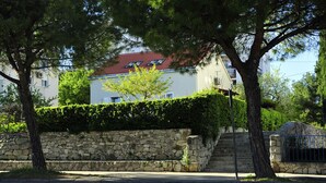 A stone wall with a staircase leading to a building with a red roof. - Green Garden apartment (Split)