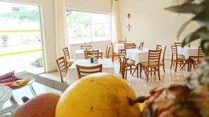 A dining area with tables and chairs, a large window, and a view of the outside. - Apart Hotel Água Limpa (Prados)