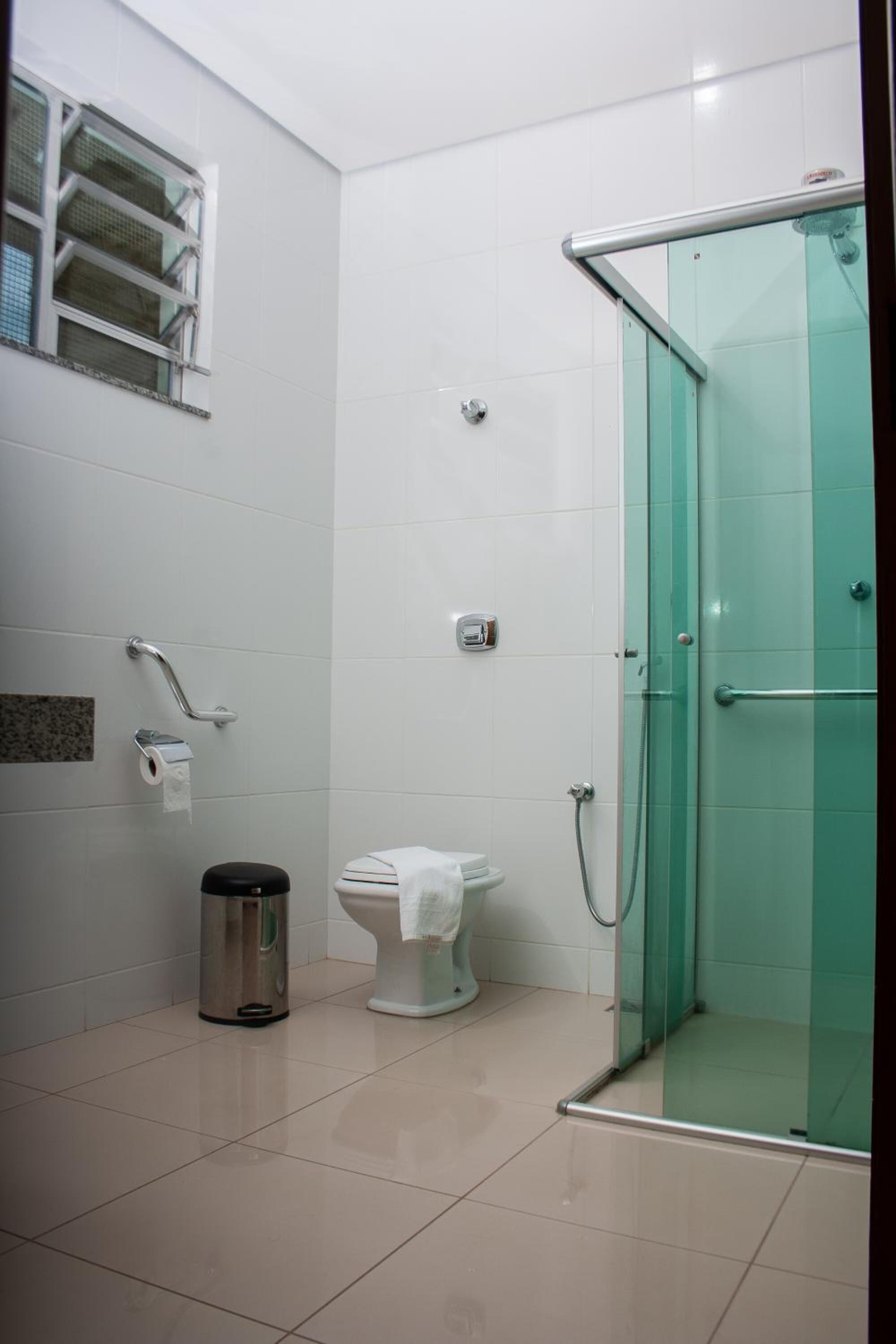 Un baño moderno con cabina de ducha de vidrio, inodoro y cubo de basura.