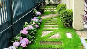 A narrow garden path with stepping stones leading to a building entrance. - Apart Hotel Água Limpa (Prados)