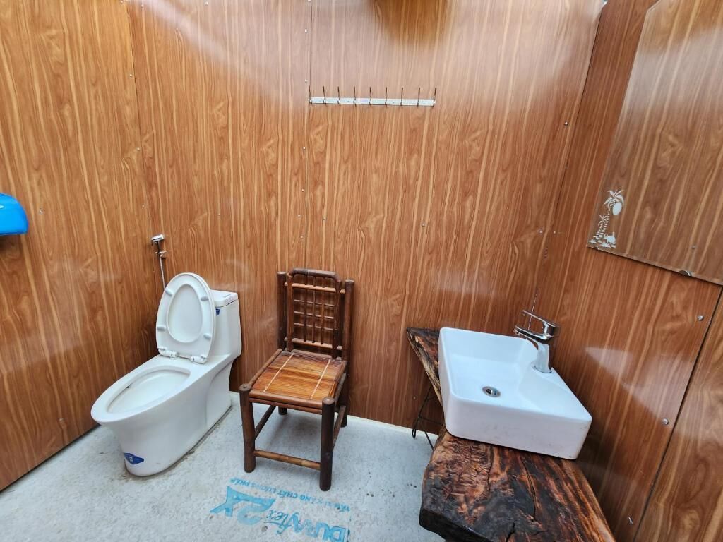 A compact bathroom with a wooden vanity, a toilet, and a sink.