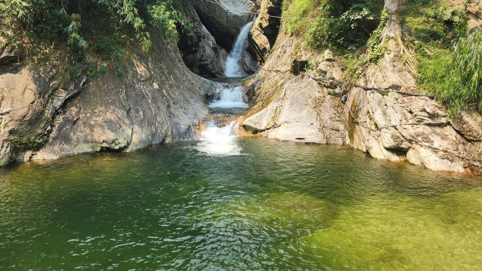 Een natuurlijke rotsformatie met een waterval en een poel.
