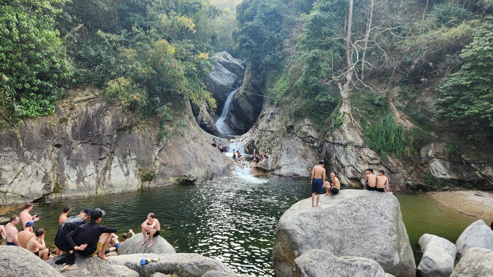 Una fuente termal natural rodeada de terreno rocoso y abundante vegetación.