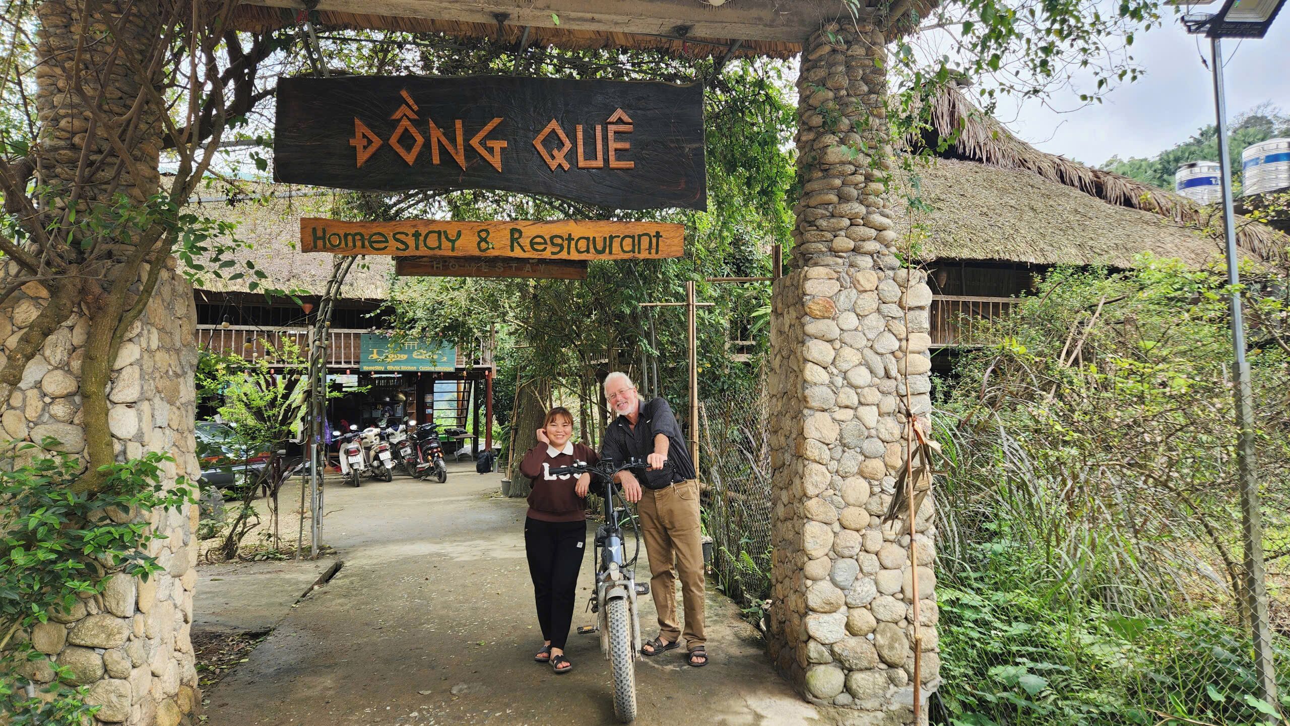 A stone archway with signs for a homestay and restaurant.