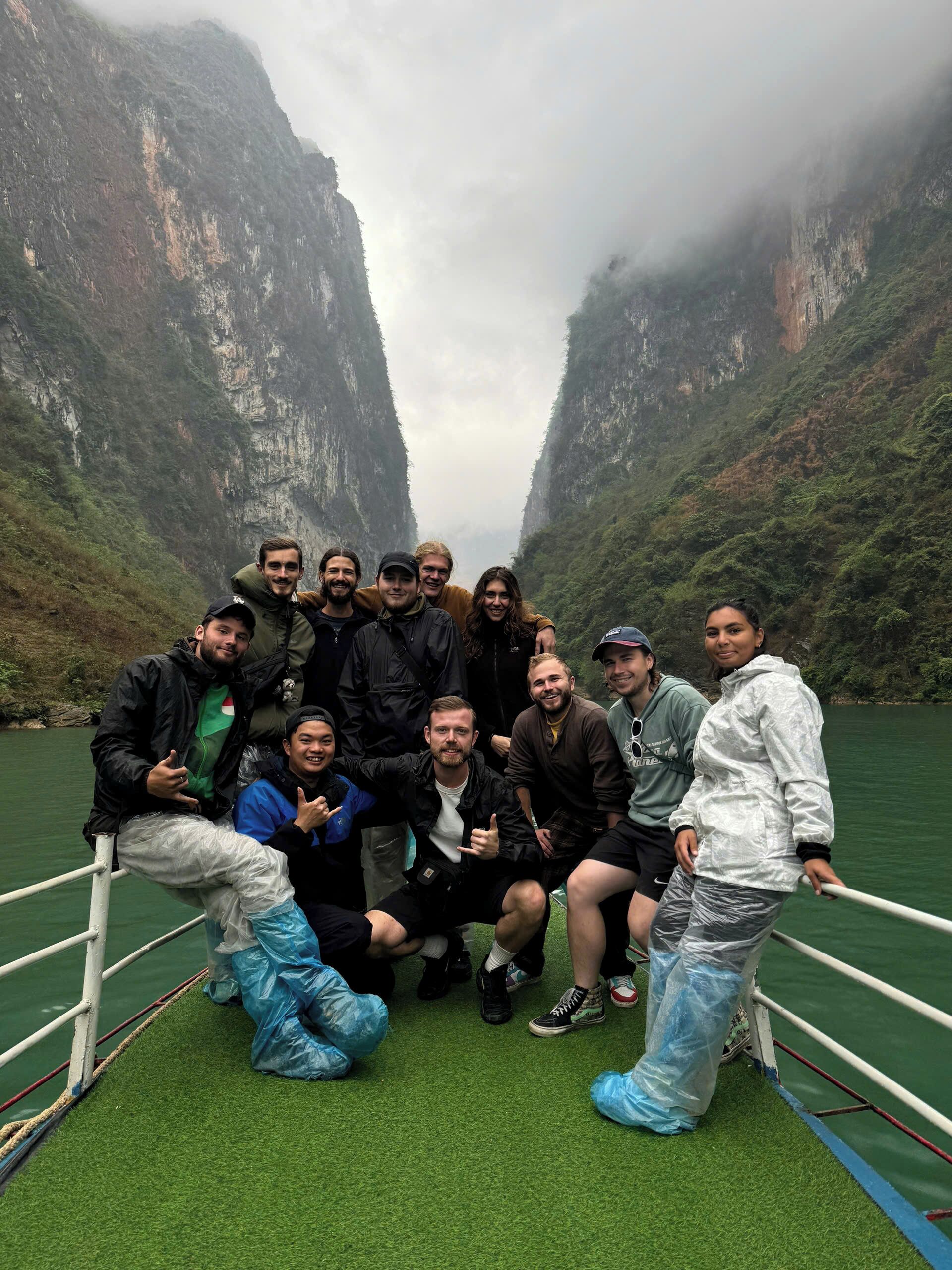 Eine Gruppe von Menschen in einem Boot, mit einer bergigen Landschaft im Hintergrund.