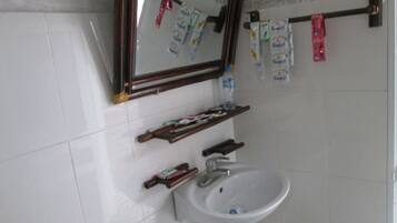 Une salle de bain avec un lavabo blanc, un miroir et des articles de toilette accrochés au mur.