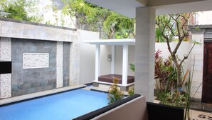 Una piscina con un banco blanco y una pequeña planta al frente.