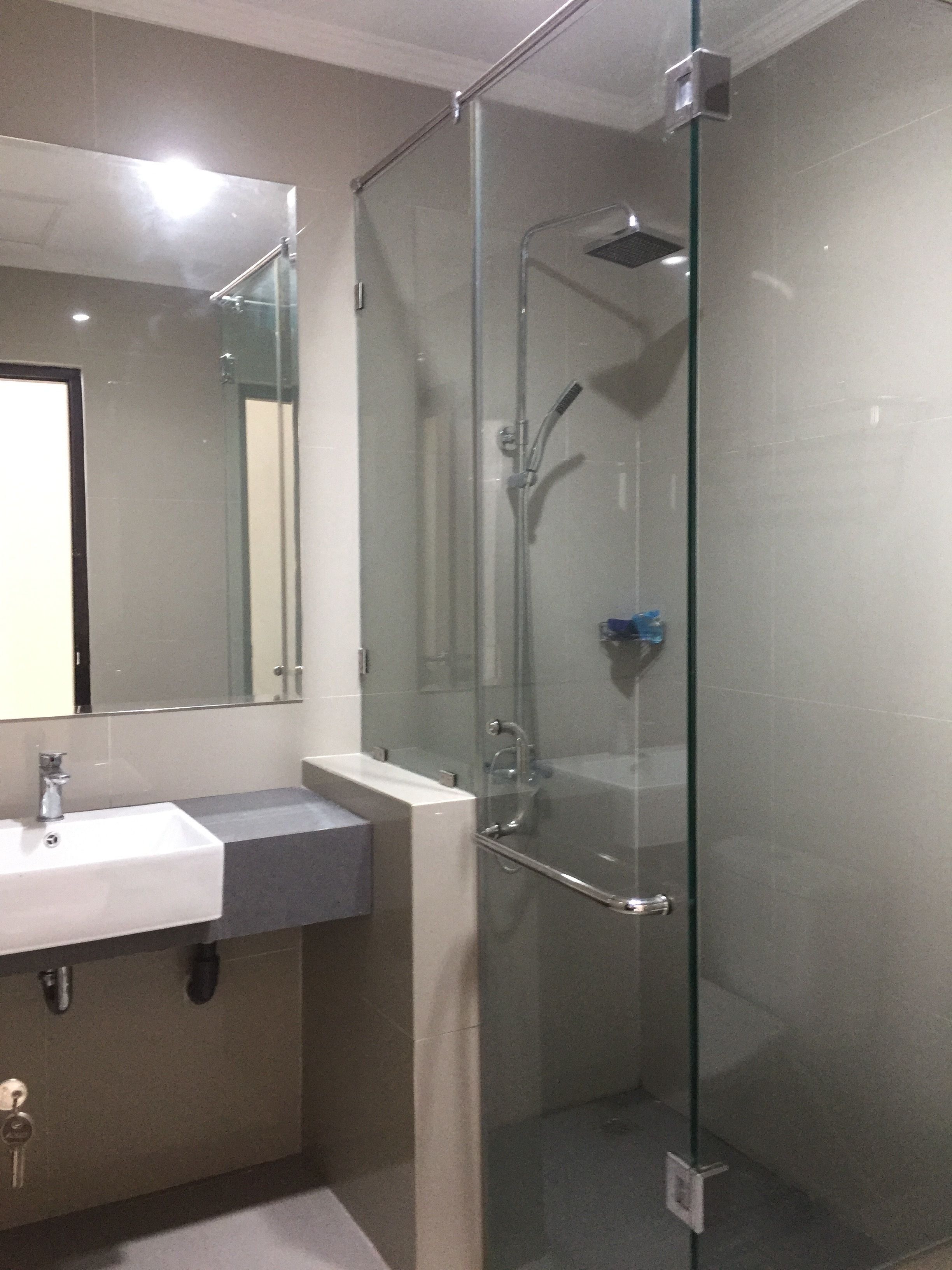 A modern bathroom with a glass-enclosed shower, a sink, and a mirror.