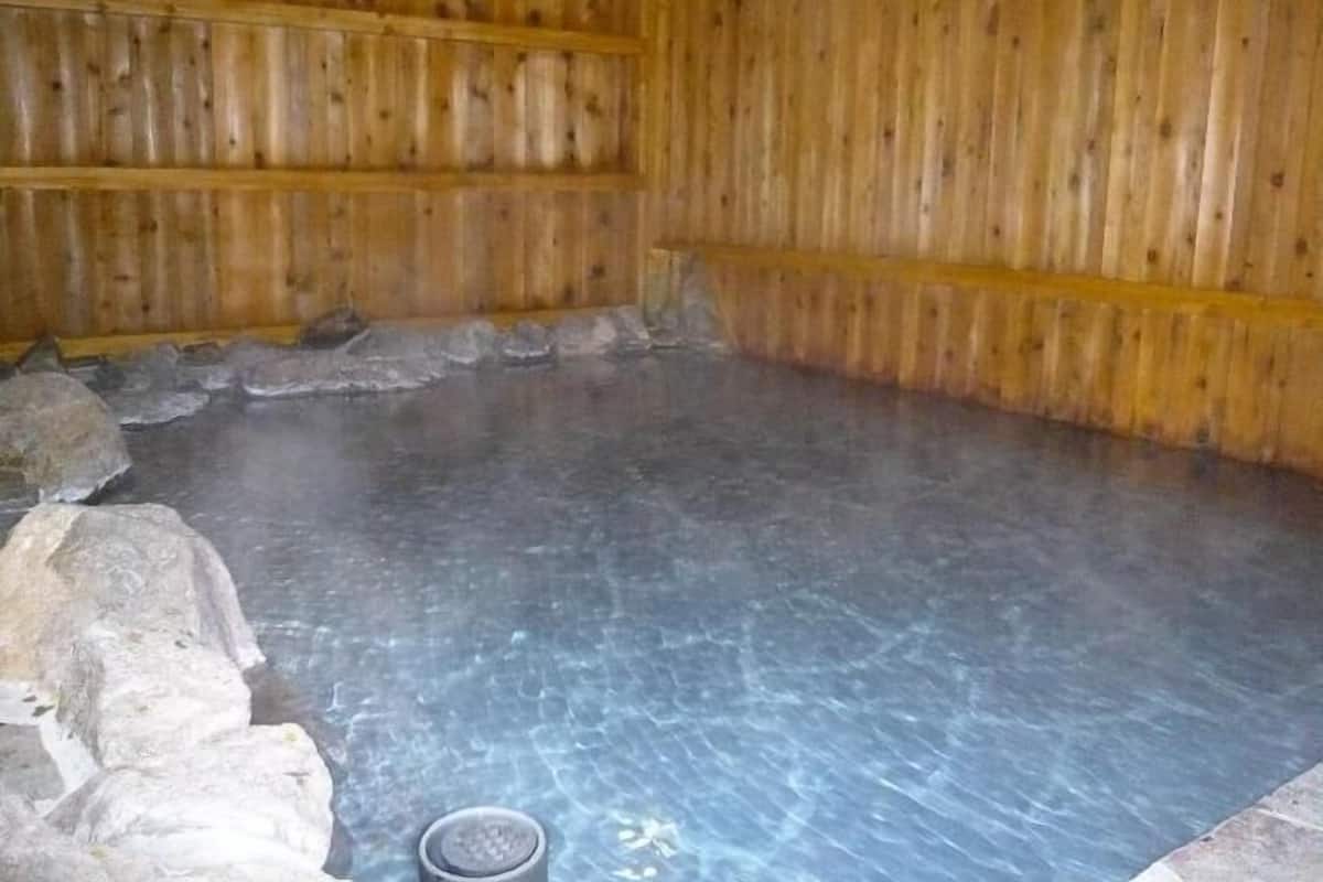 A wooden cabin interior with a stone-lined floor and a metal bucket.