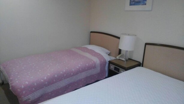 A hotel room with a single bed, a nightstand with a lamp, and a telephone. - Zao Onsen Largent Zao (Yamagata)
