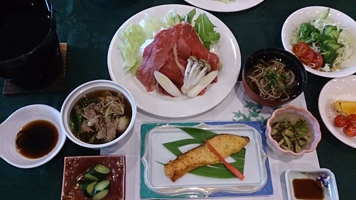 Une table garnie de différents plats, notamment de la viande, des légumes et un bol de soupe.