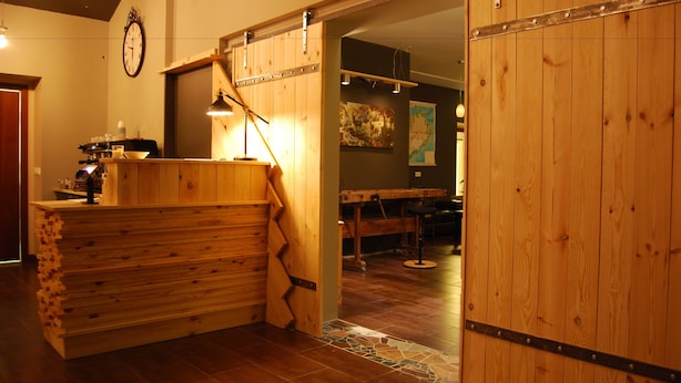 A wooden reception desk with a clock, a map on the wall, and a wooden floor. - Tehúsið Hostel (Egilsstaðir)