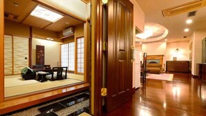 Ein traditioneller japanischer Raum mit Tatami-Böden, einer Schiebetür und einem niedrigen Tisch.