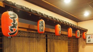 A traditional Japanese room with tatami flooring, shoji screens, and hanging orange lanterns with Japanese characters. - Hotel Osho (Tendo)
