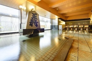 A spacious lobby with a large stone sculpture, a tiled floor, and a modern ceiling design. - Hotel Ohsho (Tendo)