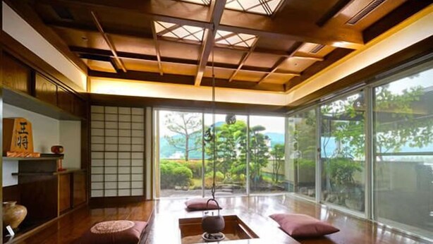 Ein traditioneller japanischer Raum mit Tatami-Bodenbelag, einem niedrigen Holztisch und verschiebbaren Shoji-Bildschirmen.