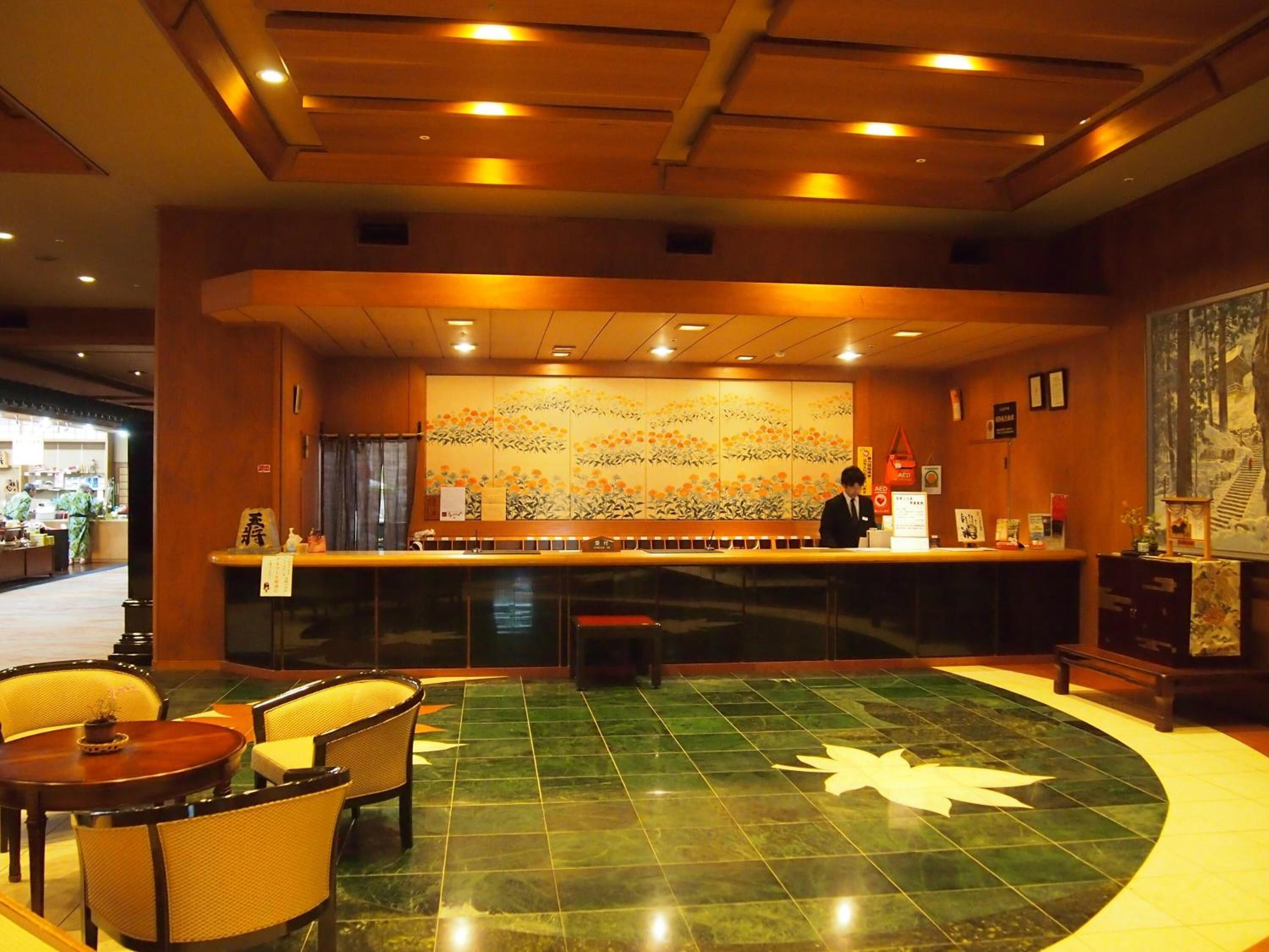 A hotel lobby with a reception desk, seating area, and a large decorative wall.