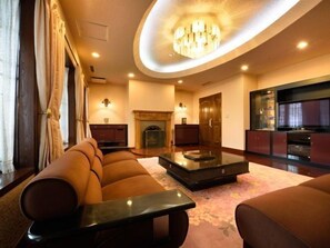 A spacious living room with a sofa set, a coffee table, a fireplace, and a television. - Hotel Ohsho (Tendo)