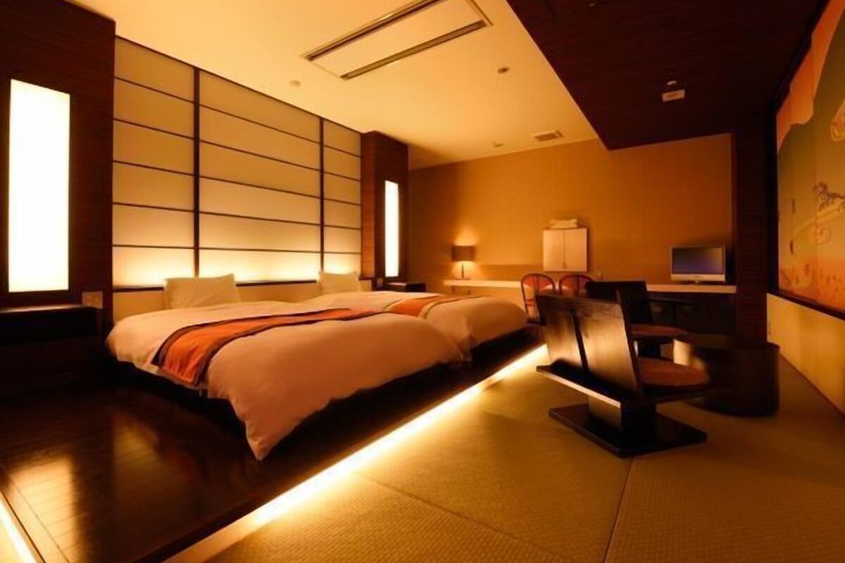 Une chambre d’hôtel avec un grand lit, un bureau avec une chaise, une télévision et un meuble fixé au mur.