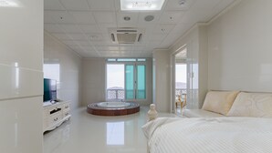 Una habitación de hotel moderna con una cama grande, una bañera redonda y un televisor sobre un mueble.