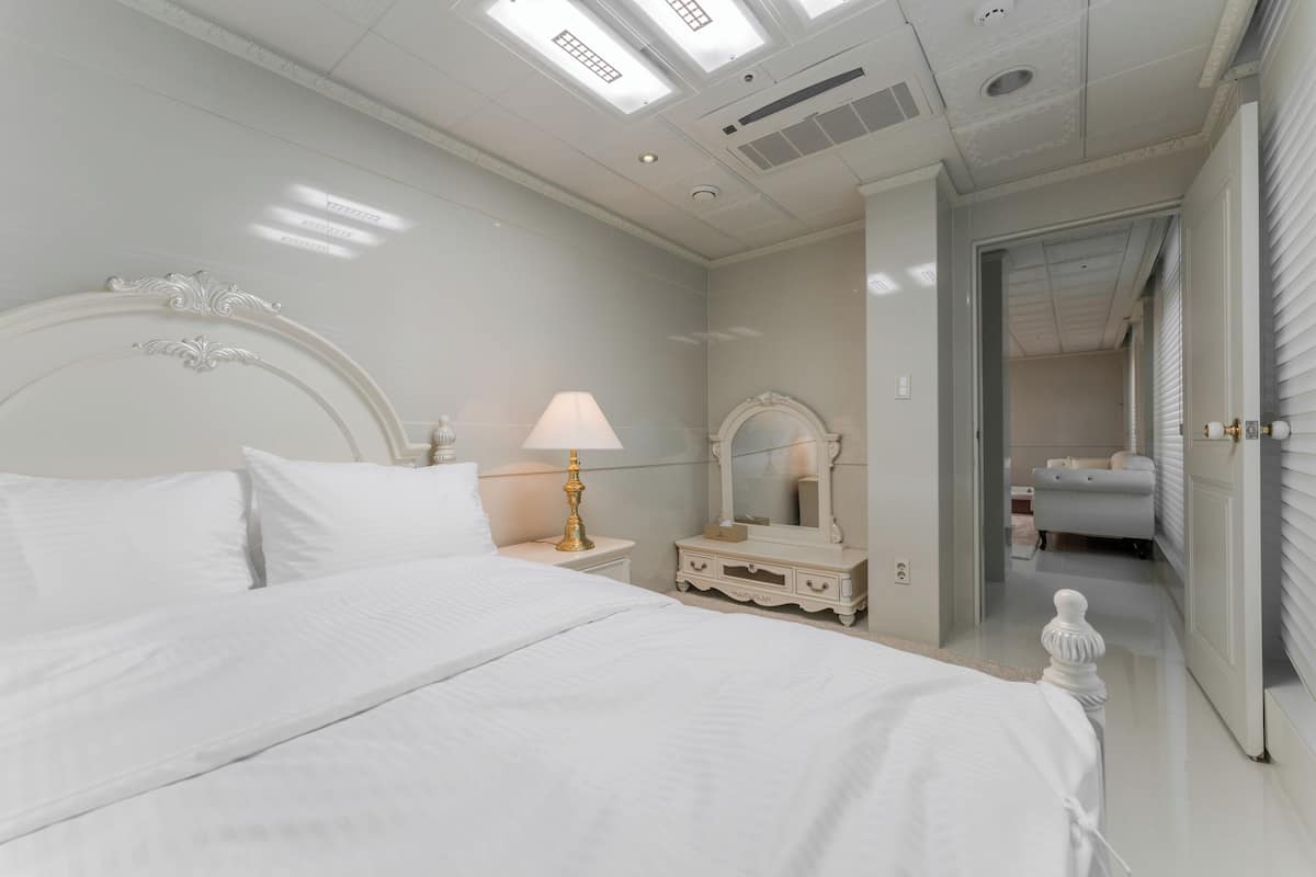 Une chambre à coucher avec un grand lit, une table de chevet avec une lampe, une commode et un miroir.